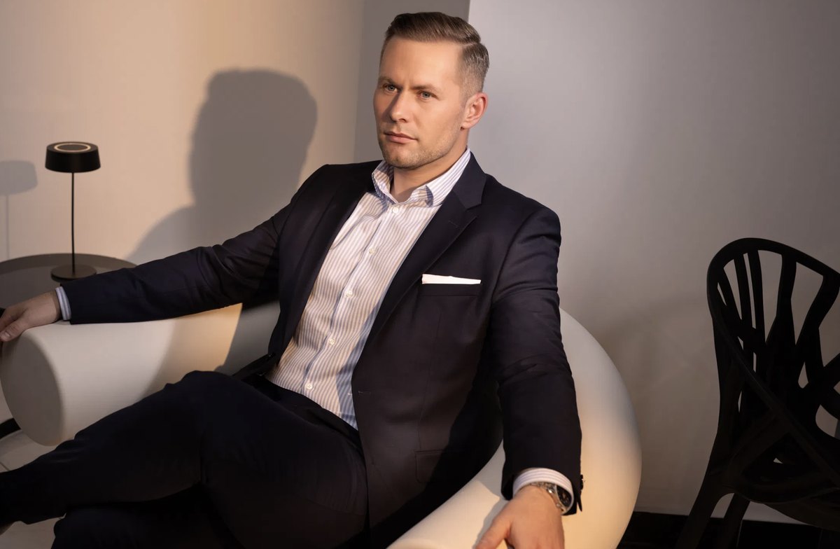 Mann im Anzug mit Einstecktuch auf hellem Sofa