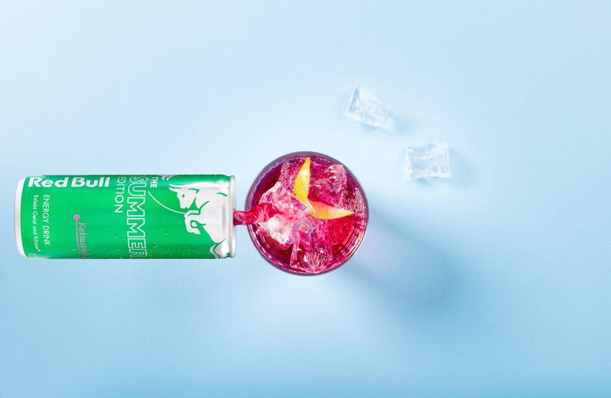 Grüne Getränkedose und Glas mit pinkem Drink von oben auf hellblauem Hintergrund