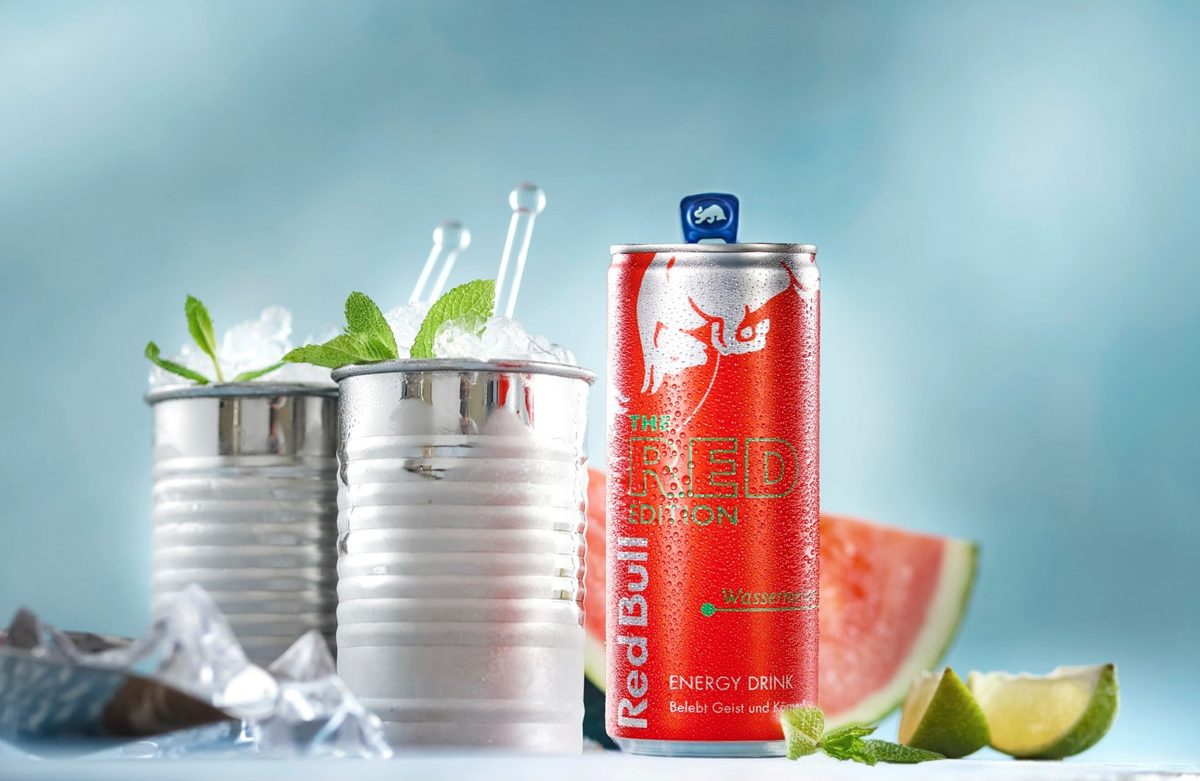 Rote Getränkedose mit Eisbechern, Melone und Limette vor hellblauem Hintergrund