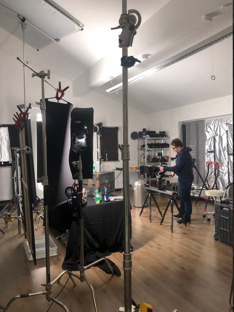 Fotograf bereitet im Studio ein Produktset zwischen Stativen und Softboxen vor