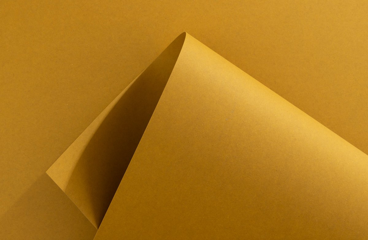 Gelber Papierbogen mit spitz eingerollter Ecke und Schlagschatten im Inneren